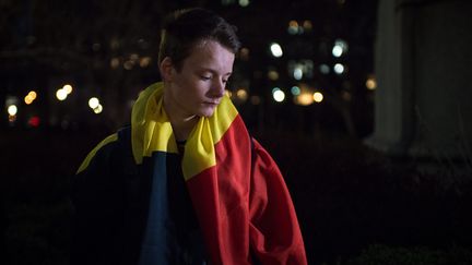 Un jeune Américain, drapeau belge sur les épaules, se recueille devant ce mémorial improvisé sur Union Square, à New York.&nbsp; (MAXPPP)