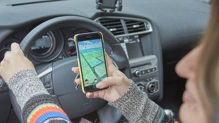 Une utilisatrice de "Pokémon Go" joue au volant de sa voiture dans les rues de Nancy, le 3 juillet 2016. (MAXPPP)