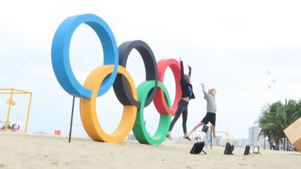 Des touristes posent devant les anneaux olympiques installés sur la plage de Copacabana, à Rio de Janeiro (Brésil), le 3 août 2016. (PIERRE GODON / FRANCETV INFO)