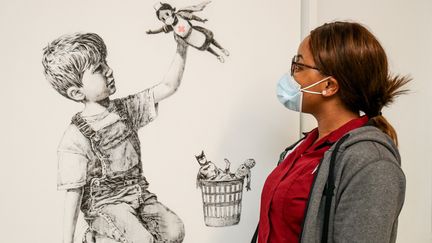 Une employée de l'hôpital de Southampton regarde l'oeuvre offerte par le street-artiste Banksy à l'établissement (7 mai 2020) (STUART MARTIN / UNIVERSITY HOSPITAL SOUTHAMPTON / AFP)