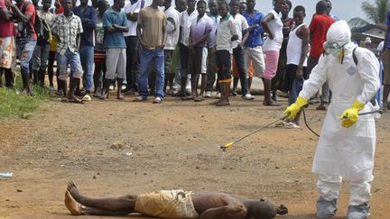 Un membre du personnel m&eacute;dical asperge de d&eacute;sinfectant le corps d'un homme suspect&eacute; d'&ecirc;tre une victime du virus Ebola &agrave; Monrovia (Lib&eacute;ria), le 4 septembre 2014. (ABBAS DULLEH / AP / SIPA)