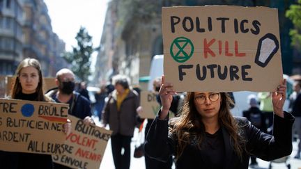 Une jeune manifestante tient une pencarte sur laquelle on lit "les politiques tuent le future", lors d'une marche du collectif Extinction Rébellion, à Toulouse (Haute-Garonne), le 26 mars 2022. (ALAIN PITTON / NURPHOTO / AFP)