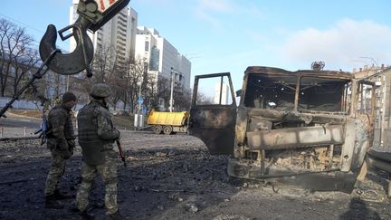 Des soldats ukrainiens devant un camion militaire calciné à Kiev, en Ukraine, le 26 février 2022. (EFREM LUKATSKY / AP / SIPA)