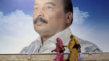 Des femmes passent à côté d'une affiche du président mauritanien sortant, Mohamed Ould Abdel Aziz, le 18 juin à Nouakchott, capitale de la Mauritanie. (Reuters - Joe Penney)