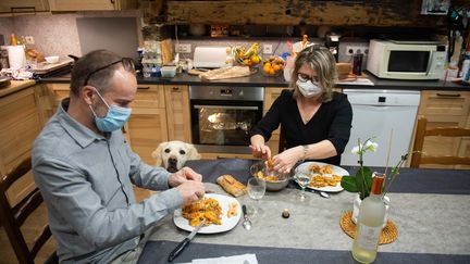 Un couple de quinquagénaires passe le repas du réveillon du Nouvel An seul, avec des masques, en tête à tête, à cause du couvre-feu et des restrictions sanitaires. (ROMAIN LONGIERAS / HANS LUCAS / AFP)