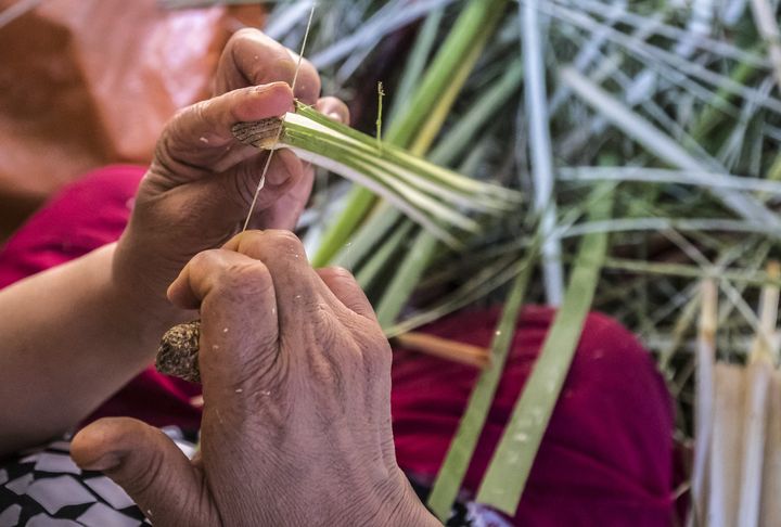 Une femme utilise un fil pour découper le papyrus en fines bandes dans l'atelier du village égyptien de al-Qaramous.&nbsp; (KHALED DESOUKI / AFP)