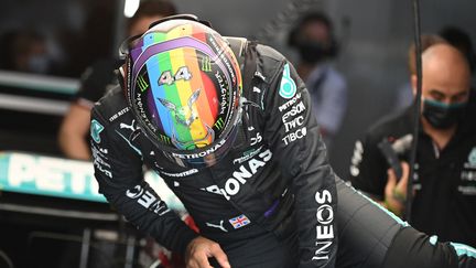 Lewis Hamilton&nbsp;s'extirpe de sa Mercedes lors des essais du premier Grand Prix du Qatar, le 19 novembre 2021. Pour l'occasion, le Britannique a changé les couleurs de son casque pour arborer celles représentant le symbole de la communauté LGBT. (ANDREJ ISAKOVIC / AFP)