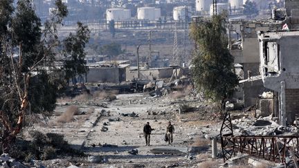 Des membres des forces pro-gouvernementales patrouillent dans un quartier d'Alep-Est (Syrie) repris aux rebelles, le 12 décembre 2016. (GEORGE OURFALIAN / AFP)