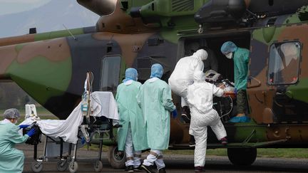 Le&nbsp;personnel médical décharge deux patients atteints de la maladie Covid-19 à leur arrivée à bord d'un hélicoptère NH90 Caiman du 1er RHC à l'aéroport de Grenoble Le Versoud,&nbsp;le 29 mars 2020. (HANDOUT / MINISTERE DES ARMEES)