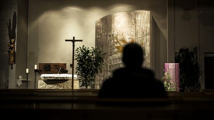 Une personne se recueille avant une messe dédiée aux victimes du père Preynat, le 7 novembre 2016 en l'église Saint-Luc de Sainte-Foy-lès-Lyon (Rhône). (JEFF PACHOUD / AFP)