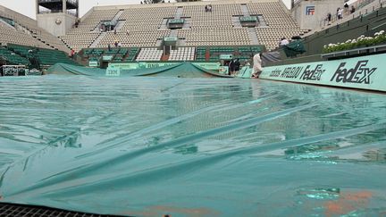 Le court Philippe-Chatrier, prot&eacute;g&eacute; par une b&acirc;che, en raison de la pluie qui s'est abattue sur Roland-Garros, mercredi 30 mai 2012.&nbsp; (JACQUES DEMARTHON / AFP)