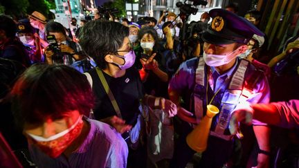 Un officier de police parle avec des manifestants opposés à la tenue des Jeux paralympiques de Tokyo, le long d'une route menant au stade national avant la cérémonie d'ouverture, le 24 août 2021. (KAZUHIRO NOGI / AFP)