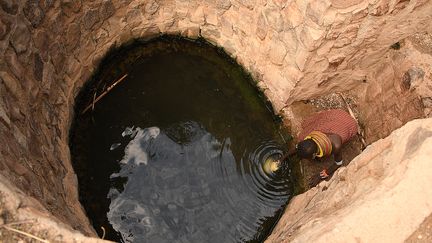 Une femme va chercher de l'eau dans un puits de la région de Loiyangalani où sont hébergées des familles touchées par la sécheresse prolongée, dans le village de Parapul, à Marsabit, dans le nord du Kenya, le 11 juillet 2022. (SIMON MAINA / AFP)