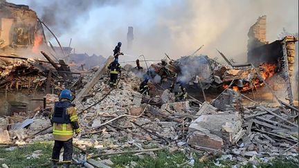 Des pompiers ukrainiens éteignent un feu sur le site de l'école bombardée le 7 mai 2022 dans un village de la région de Louhansk, dans l'est du pays. (UKRAINIAN STATE EMERGENCY SERVICE / AFP)