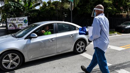 Des équipes du comté de Miami-Dade distribuent des sacs avec des masques, désinfectants et gants pour informer les gens sur la façon de se protéger du coronavirus, en Floride, le 30 juin 2020. (CHANDAN KHANNA / AFP)