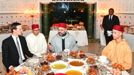 Le roi du Maroc Mohamed VI (C) et son fils, le prince héritier Moulay Hassan (D), partageant l'Iftar, dîner de rupture du jeûne du ramadan, avec Jared Kushner (G), principal conseiller du président américain Donald Trump, le 28 mai 2019 au palais royal de Salé (Rabat). (- / MOROCCAN ROYAL PALACE)