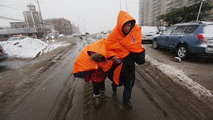 Une femme et sa fille, sinistr&eacute;es apr&egrave;s le passage du cyclone Sandy, traversent un carrefour du Queens &agrave; New York (Etats-Unis), le 7 novembre 2012, pendant une temp&ecirc;te de neige. (MARIO TAMA / GETTY IMAGES NORTH AMERICA / AFP)