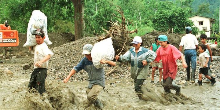 Des habitants de la ville de Portoviejo (Equateur) tentent de traverser une rivière, alors que le pont qui la surplombait a été détruit par le phénomène El Niño. (ALICIA SMITH \ AFP)