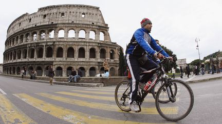 Un homme roule en v&eacute;lo pr&egrave;s du Coliseum, &agrave; Rome (Italie), le 22 janvier 2006. (ALBERTO PIZZOLI / AFP)