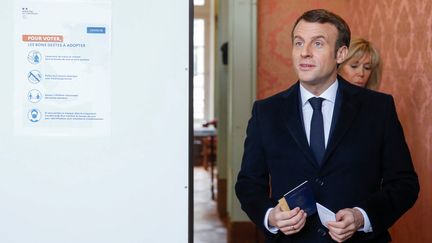 Emmanuel Macron et son épouse Brigitte Macron entrent dans des isoloirs d'un bureau de vote du Touquet (Pas-de-Calais) au premier tour des élections municipales, le 15 mars 2020. (PASCAL ROSSIGNOL / REUTERS)