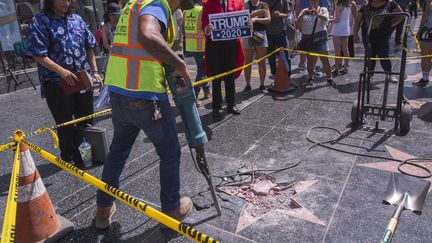 Un homme répare l'étoile de Donald Trump sur le Walk of Fame d'Hollywood, le 25 juillet 2018. (DAVID MCNEW / AFP)