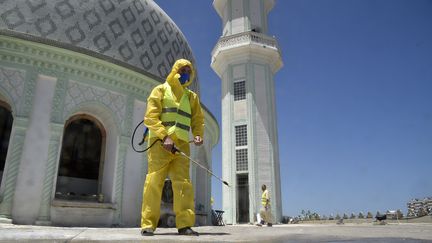 Un volontaire pulvérise une solution désinfectante sur le site de la mosquée Abou Hanifa d'Alger (Algérie), le 19 mai 2020. (RYAD KRAMDI / AFP)