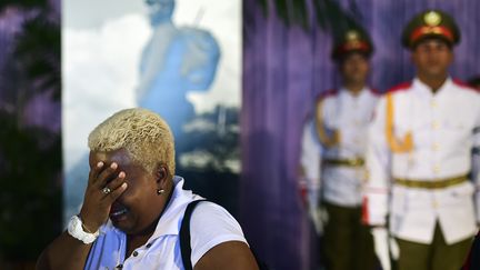 Une femme tient sa tête, tandis que des soldats monte la garde en arrière plan, au mémorial José Marti à La Havane (Cuba), lundi 28 novembre 2016. (RONALDO SCHEMIDT / AFP)