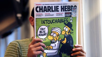 Un homme lit l'hebdomadaire "Charlie&nbsp;Hebdo" du 19 septembre 2012, &agrave; Paris. (THOMAS COEX / AFP)