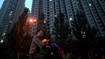 Un homme pédale sur son vélo devant un complexe immobilier du promoteur immobilier chinois Evergrande à Pékin, le 25 octobre 2021. (NOEL CELIS / AFP)