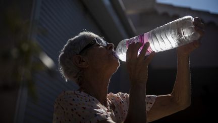 Une femme boit à Hyères (Var), pendant une vague de chaleur, le 11 juillet 2022. (MAGALI COHEN / HANS LUCAS / AFP)