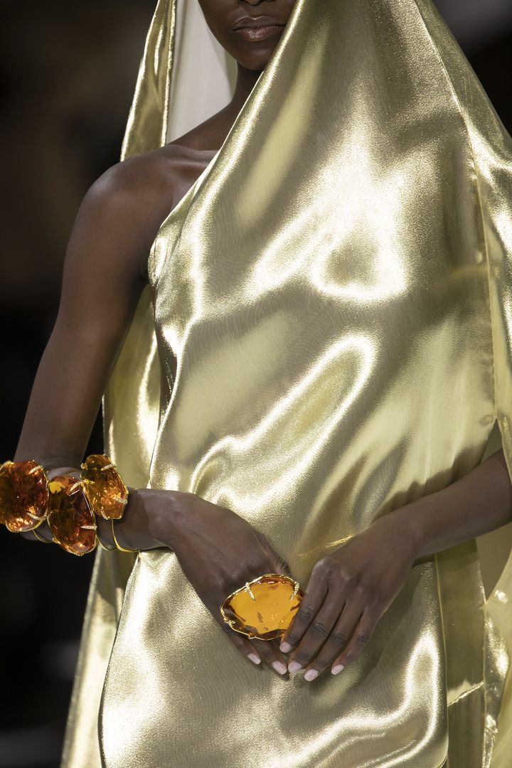 Au défilé Stéphane Rolland haute couture printemps-été 2022, le mannequin arbore une manchette et une bague aux pierres taille XXL sur une robe dorée. A Paris, le 25 janvier 2022 (VACHERON ALAIN)