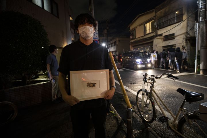 Yusuke Hasada pose avec l'oeivre qu'il a édérobée" dans la galerie SAME à Tokyo,&nbsp;&nbsp;"My Money" créée par Gabin Ito (BEHROUZ MEHRI / AFP)