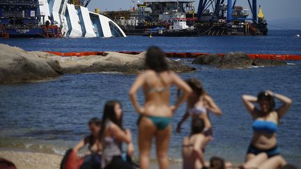 La carcasse &eacute;chou&eacute;e du Costa Concordia&nbsp;en cours de d&eacute;ment&egrave;lement est toujours le point de mire des touristes sur la plage de Giglio (Italie), le 14 mai 2013. (TONY GENTILE / REUTERS)