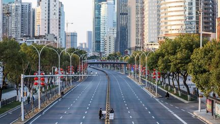 Alors épicentre de l'épidémie de Covid-19, la métropole chinoise de Wuhan est placée sous un confinement strict. Au centre de la photo, deux personnes traversent une route désertée pour livrer des légumes à un hôpital, le 20 février 2020. (AFP)