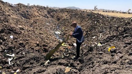 Un homme inspecte un débri de l'avion de la compagnie Ethiopian Airlines, qui s'est écrasé près de Bishoftu (Ethiopie), le 10 mars 2019. (XINHUA / ETHIOPIAN AIRLINES)