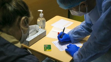 Un soignant note les informations médicales d'une patiente avant un test de dépistage du Covid-19, à Valence (Drôme), le 18 décembre 2020. (NICOLAS GUYONNET / AFP)