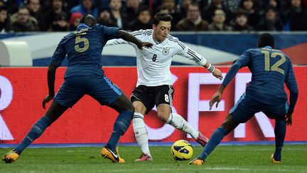 L'Allemand&nbsp;Mesut Ozil dribblant&nbsp;Mamadou Sakho (gauche) et&nbsp;Blaise Matui, le 6 f&eacute;vrier 2013 au Stade de France (Seine-saint-Denis). (FRANCK FIFE / AFP)