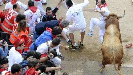 Un taureau attaque des participants des&nbsp;f&ecirc;tes traditionnelles de la San Fermin le samedi 14 juillet 2012 &agrave; Pampelune. (RAFA RIVAS / AFP)