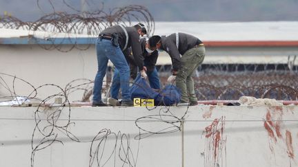 Des membres de la police équatorienne enlèvent le corps d'un détenu sur le toit d'un pavillon de la prison Guayas 1 à Guayaquil, en Équateur, le 13 novembre 2021. (NICOLA GABIRRETE / AFP)