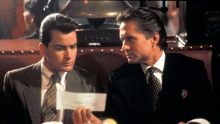 Michael Douglas et Charlie Sheen en 1987 dans le film "Wall Street" d'Oliver Stone. Rôle culte de l'acteur américain, il lui a valu l'Oscar et le Golden Globe du meilleur acteur cette année-là. (ARCHIVES DU 7EME ART)