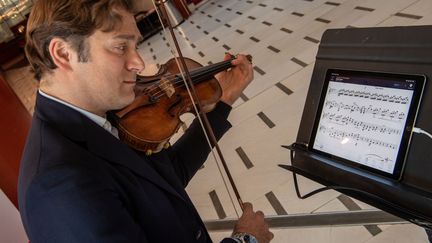 Renaud Capuçon jour avec la nouvelle application NomadPlay qui permet à un musicien de remplacer un instrument de l'orchestre sur une partition (CHRISTOPHE SIMON / AFP)