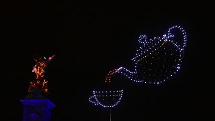 Une théière et une tasse sont dessinées par des drones au-dessus du palais de Buckingham, le 4 juin 2022, à Londres. (PAUL ELLIS / AFP)