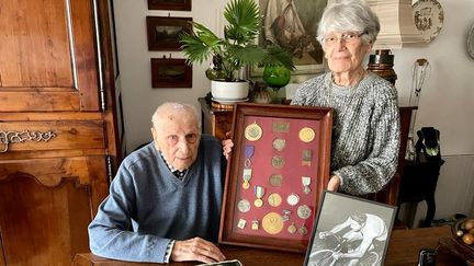 Charles Coste, champion olympique aux Jeux de Londres en 1948, et aujourd'hui âgé de 98 ans. Sa femme Yvette tient entre ses mains un cadre rassemblant toutes les médailles de son mari. (APOLLINE MERLE / FRANCEINFO SPORT)