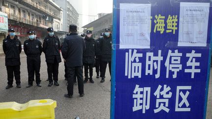 Des agents de sécurité se tiennent devant le marché de Wuhan, en Chine, où une&nbsp;mystérieuse pneumonie serait apparue, le 12 janvier 2020. (NOEL CELIS / AFP)