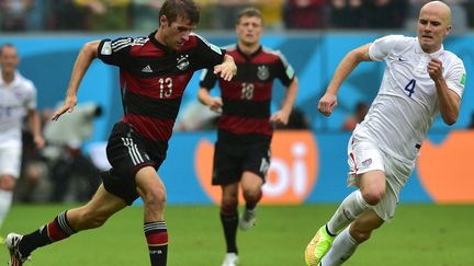 L'Allemand Thomas M&uuml;ller est poursuivi par l'Am&eacute;ricain Michael Bradley, le 26 juin 2014, lors d'un match de la Coupe du monde &agrave; Recife (Br&eacute;sil). (NELSON ALMEIDA / AFP)