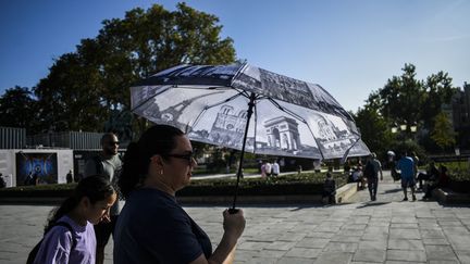 Faced with intense heat, a passerby shades herself under an umbrella on October 2, 2023 in Paris.  (MAGALI COHEN / HANS LUCAS / AFP)