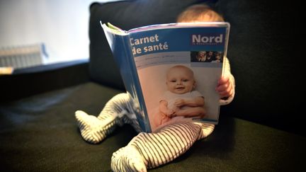 Un bébé feuilletant son carnet de santé à Valenciennes (Nord), le 2 janvier 2018. (MAXPPP)