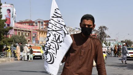 Un homme portant le drapeau des talibans dans la ville afghane de Mazâr-e Charîf, le 20 août 2021. (STRINGER / SPUTNIK / AFP)