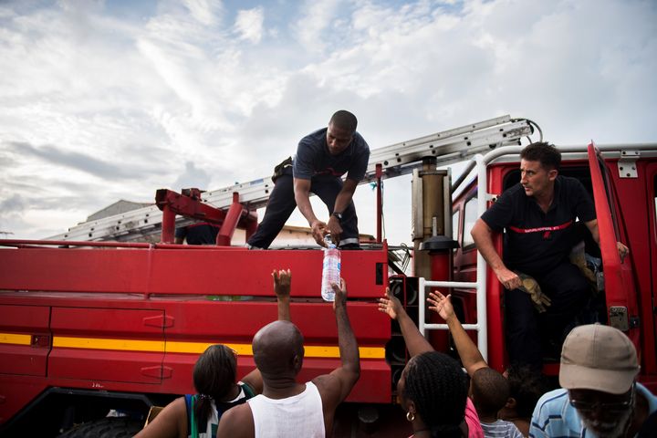 Après le passage de l'ouragan Irma, des pompiers distribuent de l'eau&nbsp;à des habitants du Marigot, le 10 septembre 2017, sur l'île de Saint-Martin. (MARTIN BUREAU / AFP)