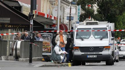 Des membres de la police scientifique rel&egrave;vent des indices, le 4 juin 2012, sur un fourgon blind&eacute; devant une agence BNP Paribas, &agrave; Aubervilliers (Seine-Saint-Denis), apr&egrave;s une attaque par des malfaiteurs arm&eacute;s. (THOMAS SAMSON / AFP)